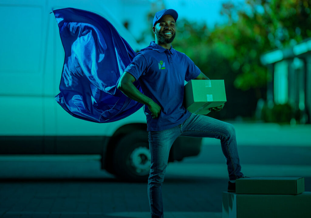 GAW Delivery Driver wearing a superhero cape holding a parcel with delivery van in the background